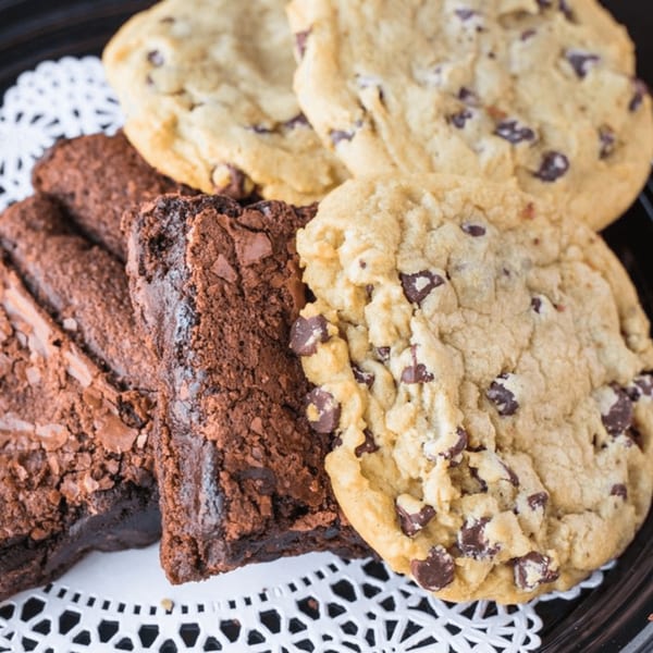 A platter of Rick's DeliCafe chocolate chip cookies and rich brownies on a white doily.