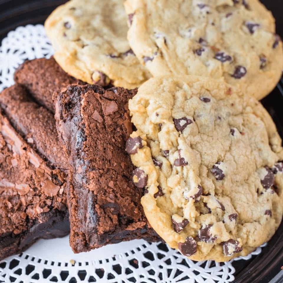 A platter of Rick's DeliCafe chocolate chip cookies and rich brownies on a white doily.