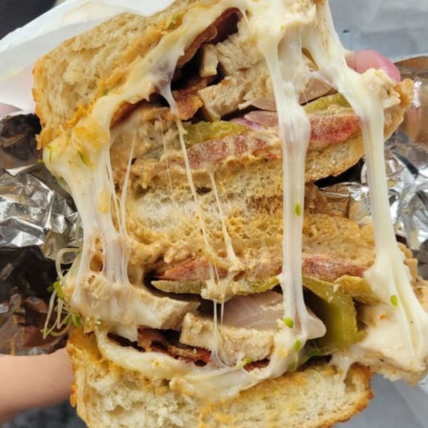 A large, cheesy deli sandwich from Ricks DeliCafe, with melted cheese stretching between the halves.